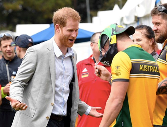 Prince Harry, Duke of Sussex laughs as an Invictus competitor puts a pair of swimming trunks on his head. Getty